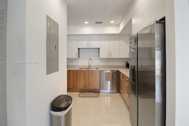 kitchen featuring a sink, electric panel, stainless steel appliances, brown cabinetry, and light countertops