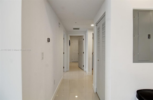 hall with electric panel, light tile patterned flooring, and baseboards