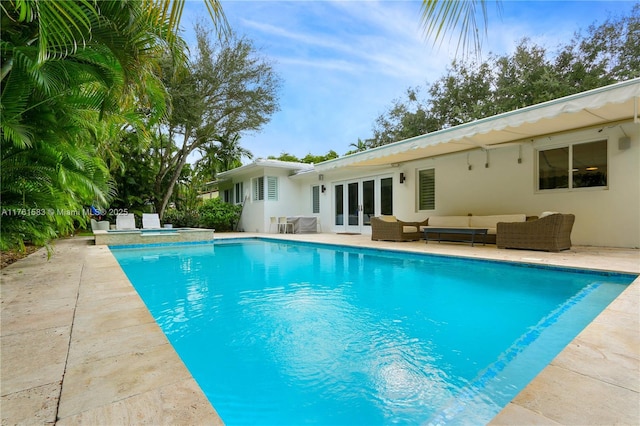 outdoor pool with a patio area, french doors, an in ground hot tub, and an outdoor hangout area