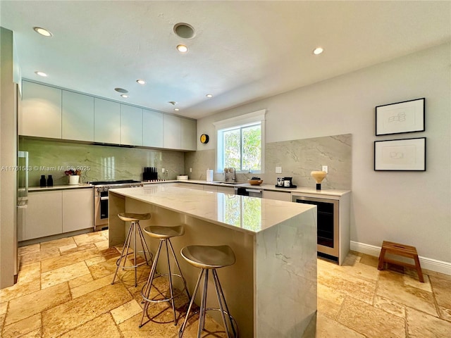 kitchen featuring stainless steel range, a sink, stone tile floors, a center island, and wine cooler