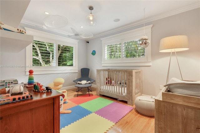 bedroom featuring a nursery area, wood finished floors, and ornamental molding