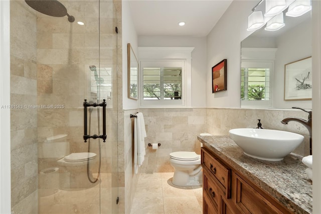 bathroom featuring a wainscoted wall, toilet, tile walls, a shower stall, and vanity