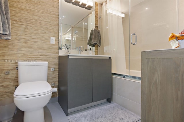 bathroom with toilet, tile walls, vanity, and a shower with shower door