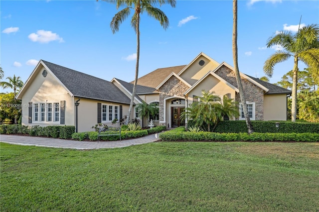 view of front of house with a front lawn, stone siding, and stucco siding