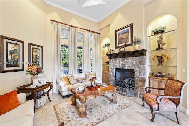 living area with tile patterned floors, built in shelves, a stone fireplace, and ornamental molding