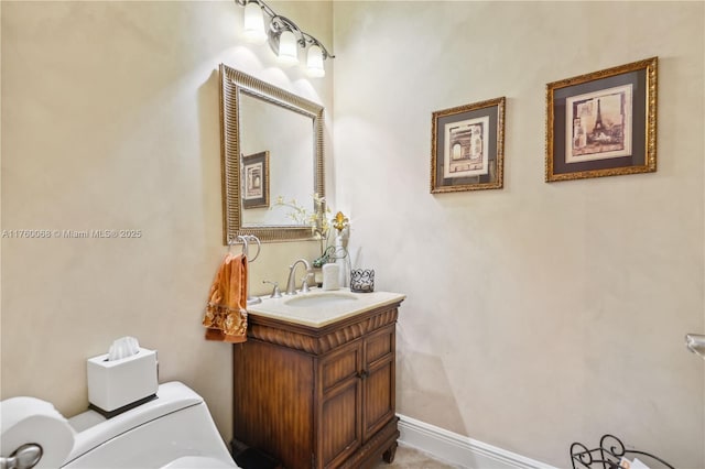 half bathroom featuring vanity, toilet, and baseboards