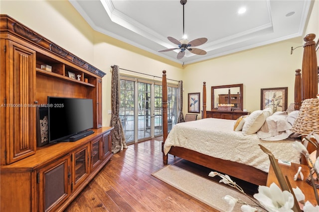 bedroom featuring hardwood / wood-style floors, a raised ceiling, access to outside, and crown molding