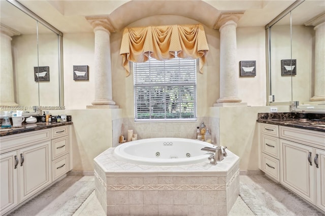 bathroom with a tub with jets, vanity, and ornate columns