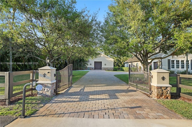 exterior space featuring a fenced front yard, a lawn, decorative driveway, and a gate