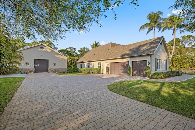 view of front of home featuring stone siding, stucco siding, decorative driveway, and a front lawn