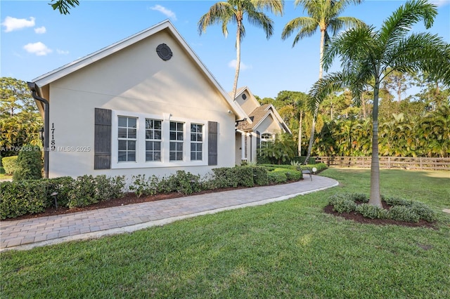 view of property exterior with a lawn, fence, and stucco siding