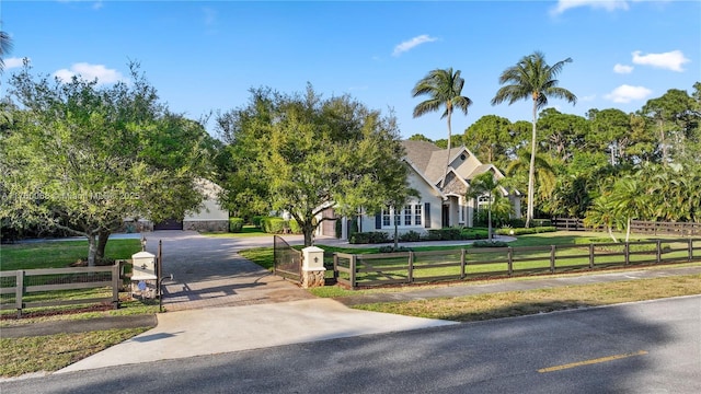 view of front facade with a fenced front yard, decorative driveway, a front yard, and a gate