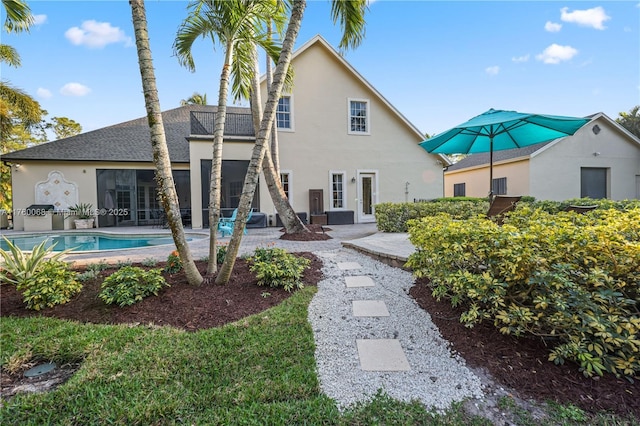 back of house featuring a patio, an outdoor pool, and stucco siding