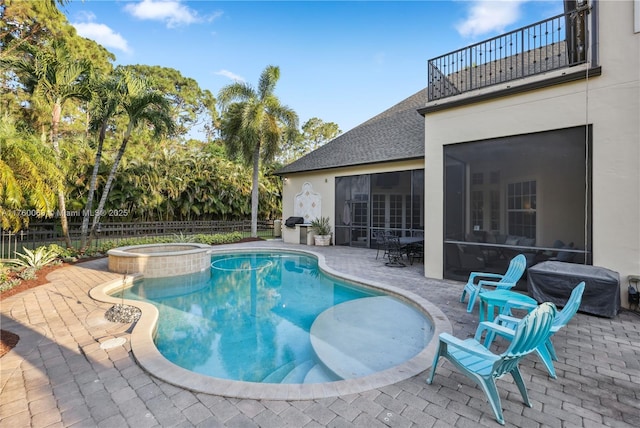 view of swimming pool with a patio, fence, a pool with connected hot tub, a sunroom, and grilling area