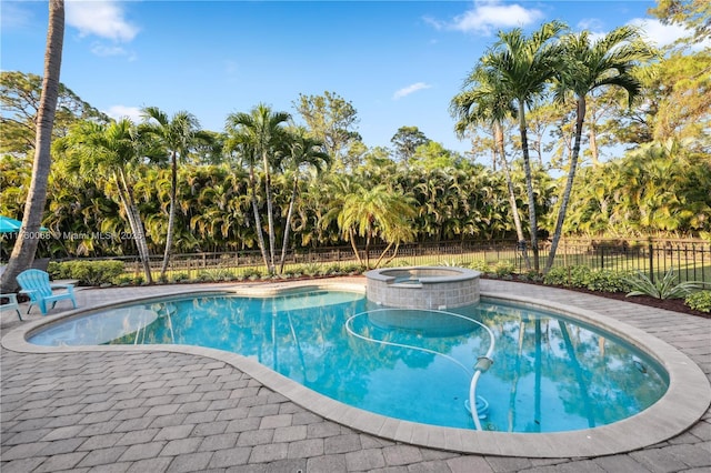 view of pool featuring a pool with connected hot tub and fence