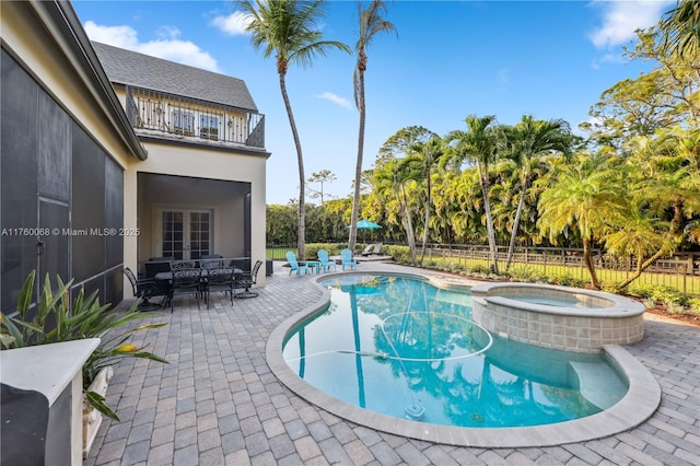 view of pool with french doors, a pool with connected hot tub, a patio, and fence