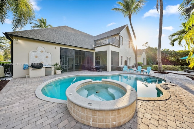 view of swimming pool featuring a patio area, a grill, a pool with connected hot tub, and a sunroom