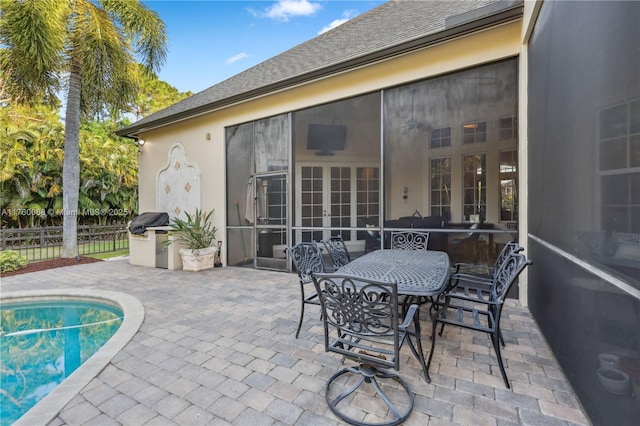 view of patio with outdoor dining space, a fenced in pool, fence, and a sunroom