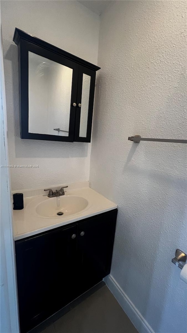 bathroom featuring baseboards, vanity, and a textured wall