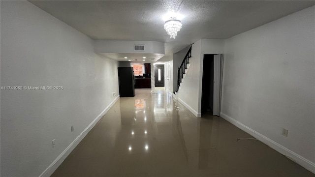 hall with visible vents, an inviting chandelier, stairs, and baseboards