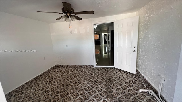 unfurnished room with carpet flooring, a ceiling fan, and a textured wall