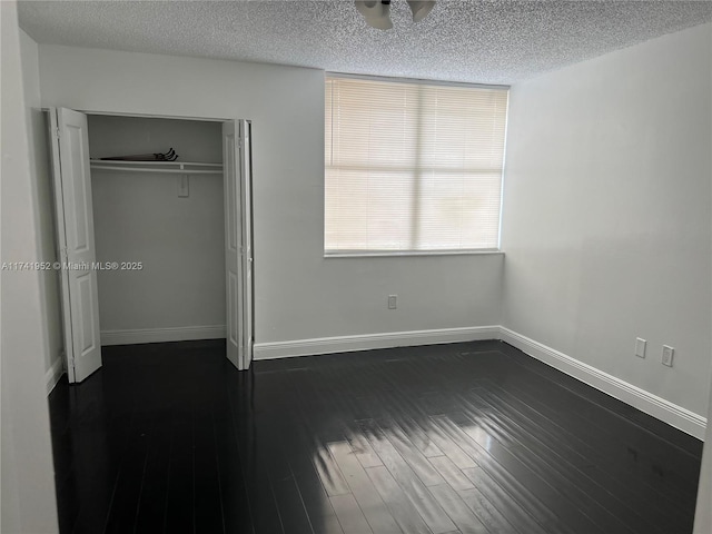 unfurnished bedroom with baseboards, a textured ceiling, and dark wood finished floors