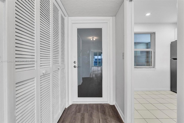 hallway featuring wood finished floors, baseboards, and a textured ceiling