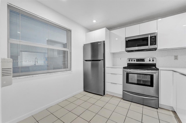 kitchen with appliances with stainless steel finishes, light tile patterned flooring, light countertops, and white cabinetry