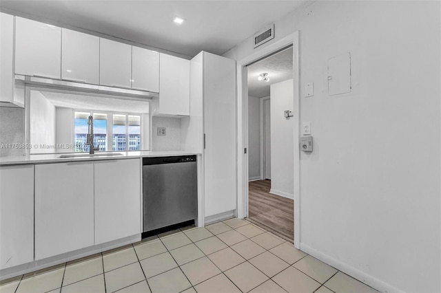 kitchen with visible vents, white cabinetry, a sink, light countertops, and stainless steel dishwasher