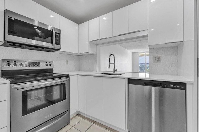 kitchen with a sink, stainless steel appliances, white cabinets, and light countertops