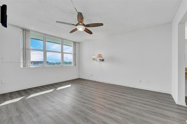 spare room featuring baseboards, a textured ceiling, ceiling fan, and wood finished floors