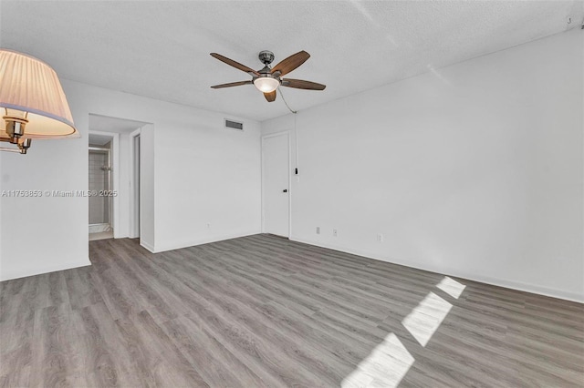 empty room featuring visible vents, a textured ceiling, a ceiling fan, and wood finished floors