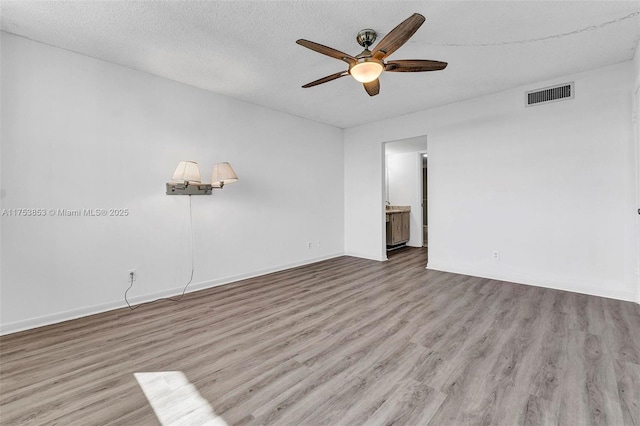 unfurnished room featuring visible vents, a textured ceiling, a ceiling fan, and wood finished floors