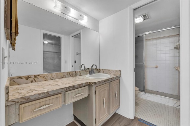 bathroom featuring vanity, a shower stall, toilet, and wood finished floors