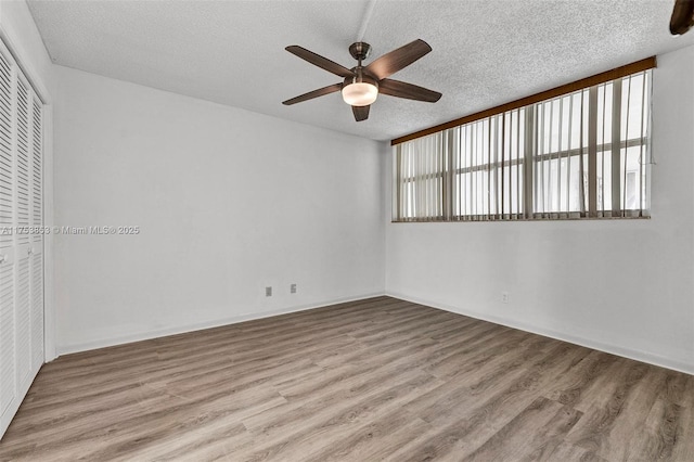 unfurnished room with a ceiling fan, wood finished floors, and a textured ceiling