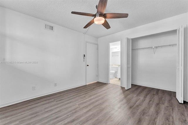 unfurnished bedroom with visible vents, connected bathroom, wood finished floors, a closet, and a textured ceiling