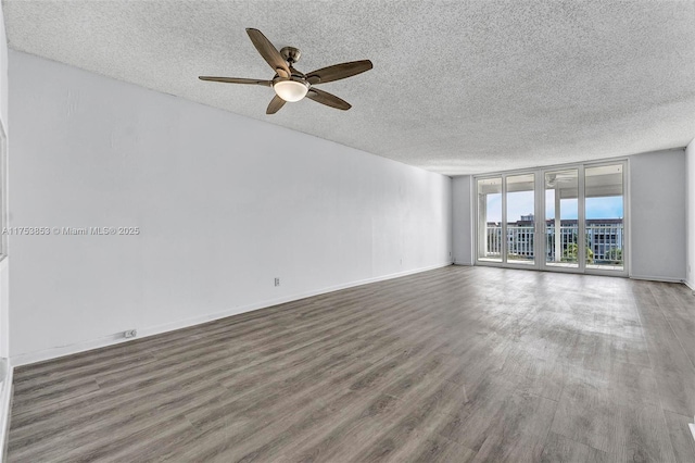 spare room featuring a wall of windows, baseboards, a textured ceiling, and wood finished floors