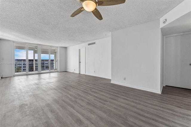 empty room with a ceiling fan, visible vents, wood finished floors, baseboards, and a textured ceiling