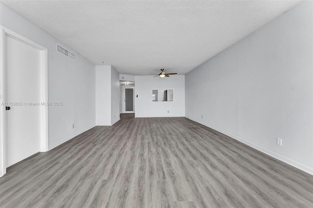 unfurnished living room featuring visible vents, a textured ceiling, wood finished floors, and a ceiling fan