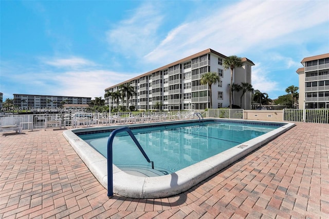 community pool with a patio area and fence