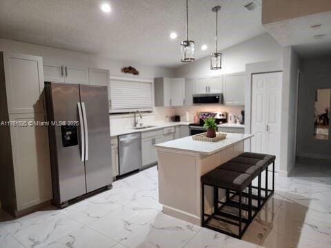 kitchen featuring a center island, marble finish floor, appliances with stainless steel finishes, and a sink