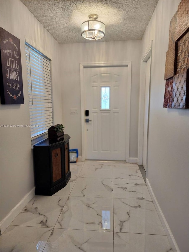 foyer featuring baseboards, marble finish floor, and a textured ceiling