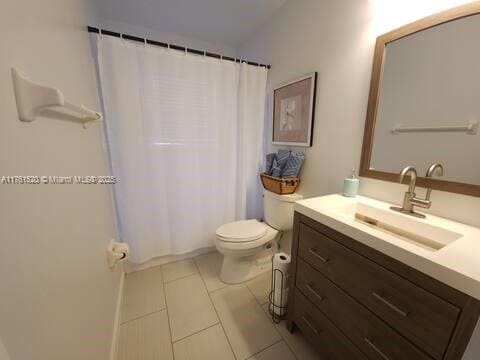 bathroom with a shower with shower curtain, toilet, vanity, and tile patterned flooring