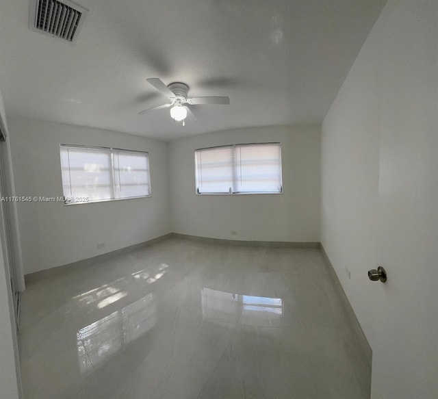 spare room featuring visible vents, ceiling fan, and baseboards