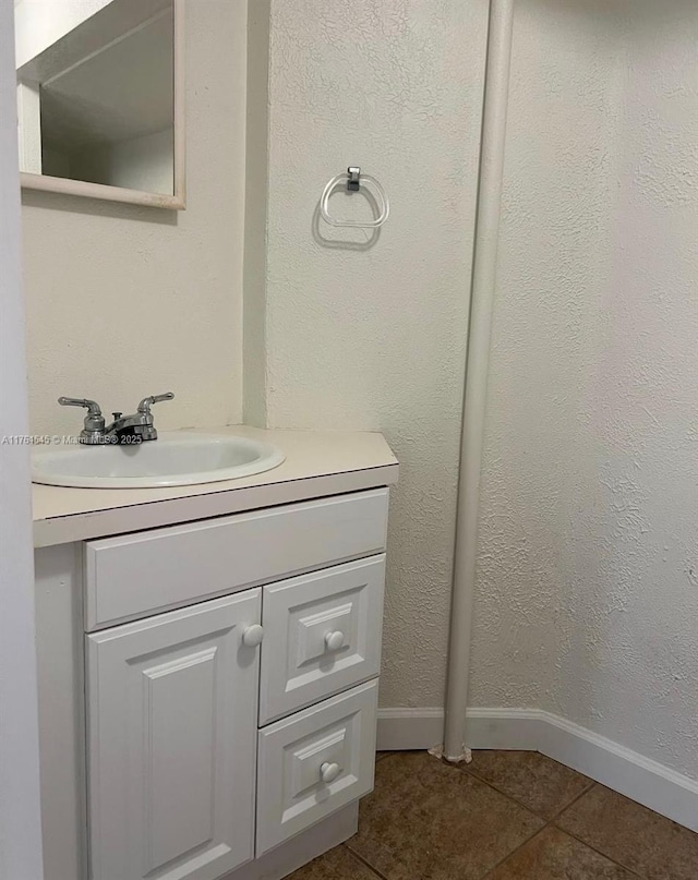 bathroom with vanity, tile patterned floors, a textured wall, and baseboards