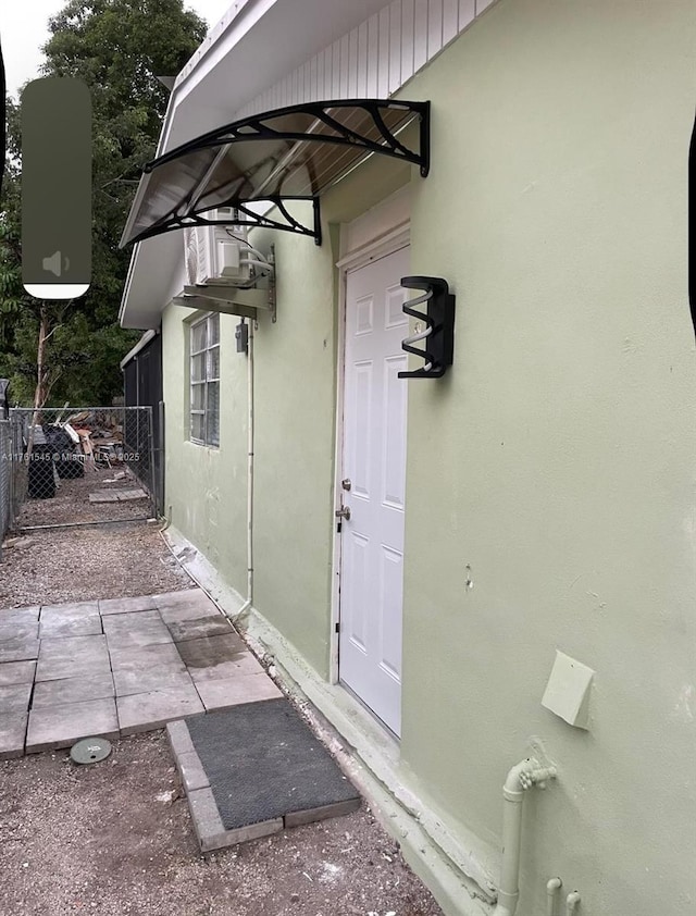 entrance to property with a gate, stucco siding, and fence