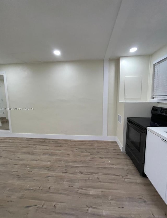 kitchen with light wood finished floors, baseboards, recessed lighting, white cabinetry, and black / electric stove