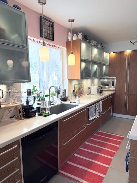 kitchen featuring dishwasher, stainless steel microwave, light countertops, and a sink