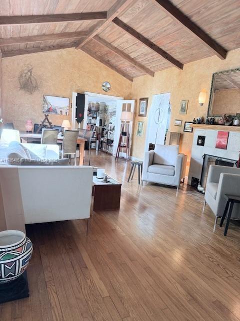 living area featuring beamed ceiling, high vaulted ceiling, wood ceiling, and wood finished floors