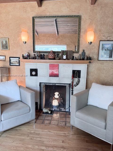 1643 Nethia Dr, Miami, FL 33133 - living area featuring wood finished floors, beamed ceiling, and a tiled fireplace
